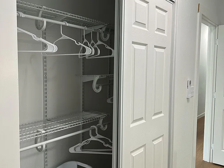 Hallway closet with sliding doors and wire shelving for organized storage.