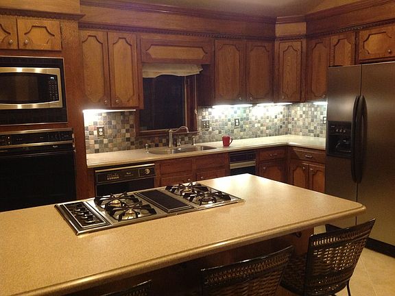 Modern kitchen, new gas cooktop, stainless steel side-by-side refrigerator, microwave, electric stove, open plan for conversations around cooking island, trash compactor, pantry.
