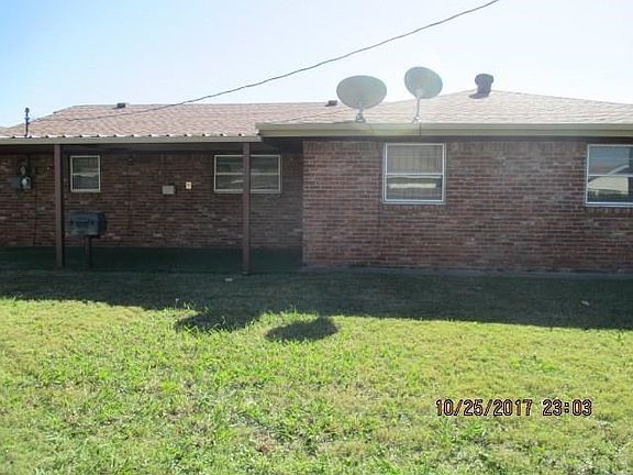 Back of house features covered patio, gas grill and wood fence.