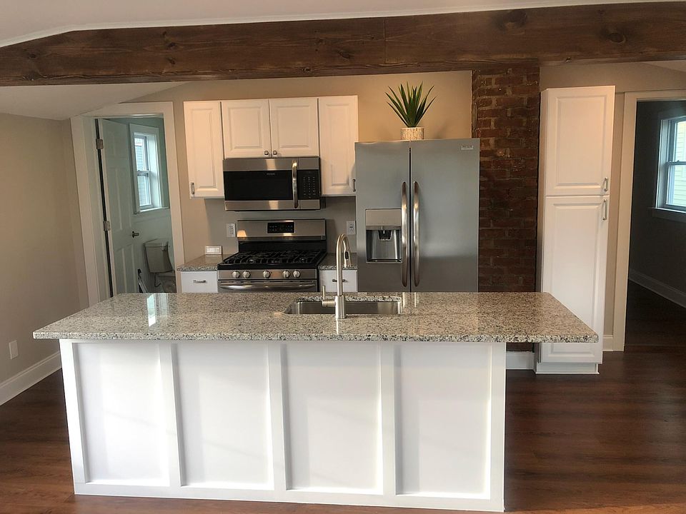 Great room, looking at kitchen area with wood beam, pantry, granite countertops and stainless steal appliances.