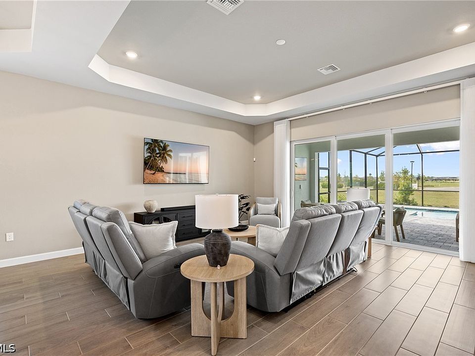 Open great room with tray ceiling and a wall of sliding glass doors out to a screened lanai and pool, Punta Gorda, Florida