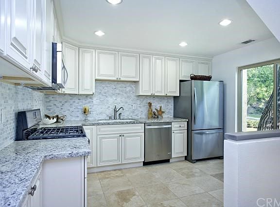 Remodeled kitchen features granite counters & tile back-splash with stainless applicances
