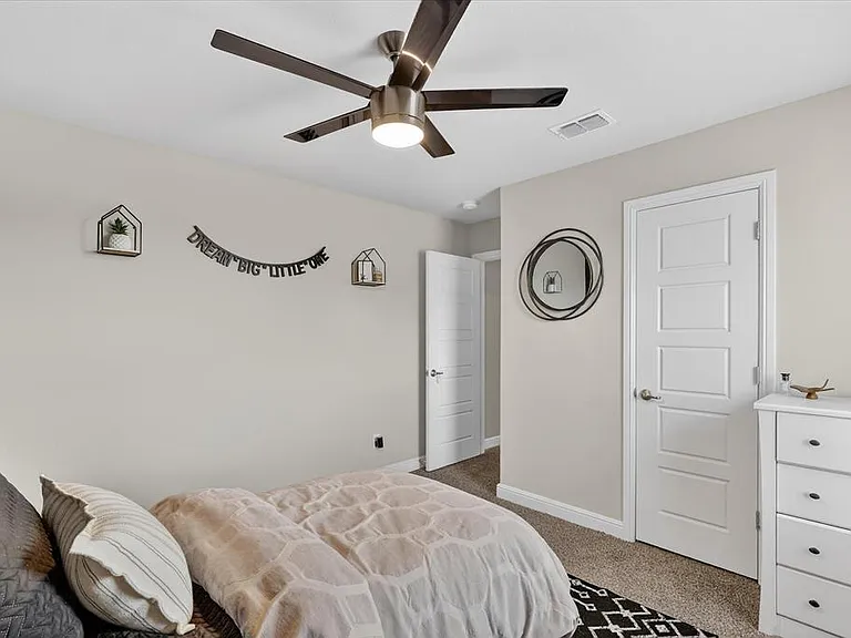 Bedroom featuring a contemporary ceiling fan with integrated lighting, neutral wall tones, and carpet flooring