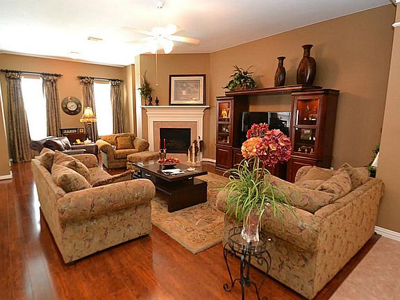 Spacious family room featuring hardwood floors, ceiling fan with light fixture and a fireplace with gas logs.