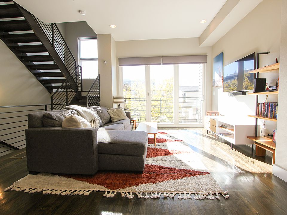 The living room has tons of natural light, privacy curtains, a Smart TV, a comfortable sofa, and an attached patio with glass doors that can open.