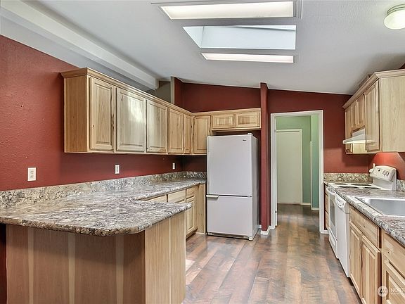 View from dining to kitchen, nice included appliances and utility room is straight ahead. With the skylights above, you rarely need to turn on your lights! >