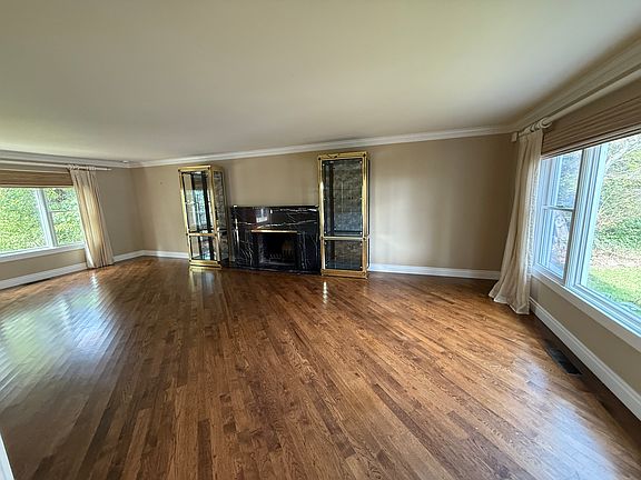 spacious living room w marble fireplace; hardwood floors, custom rattan window shades and draperies