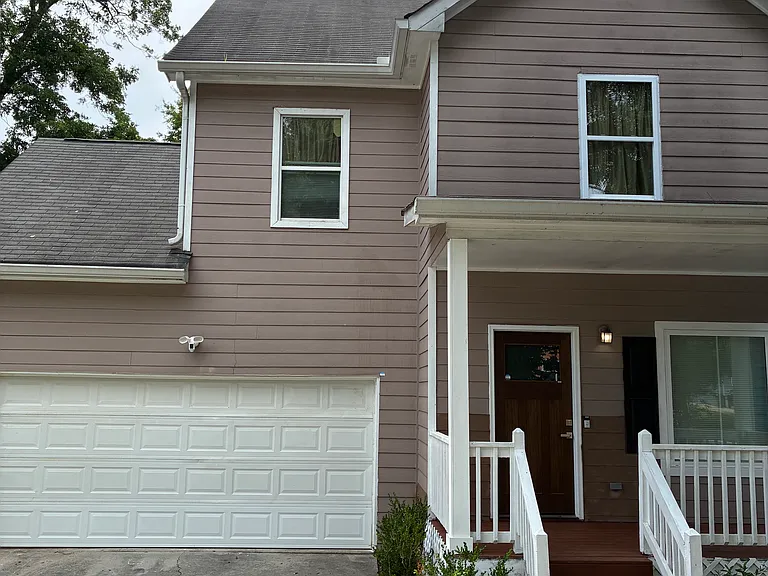 Exterior of home with beautiful wood door and attached two car garage with driveway and security camera.