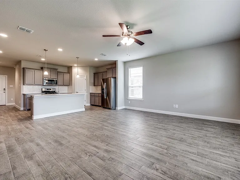 Unfurnished living room featuring ceiling fan and light hardwood / wood-style flooring