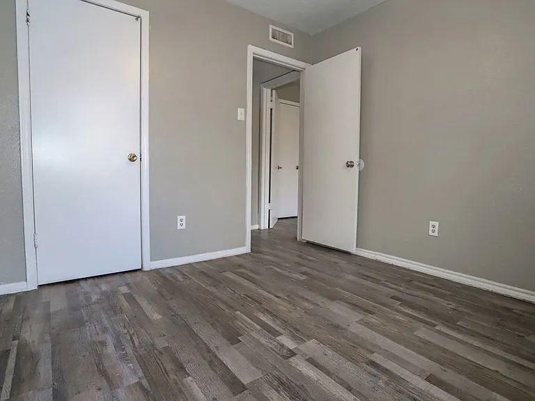 Spacious bedroom with wood-style flooring.
