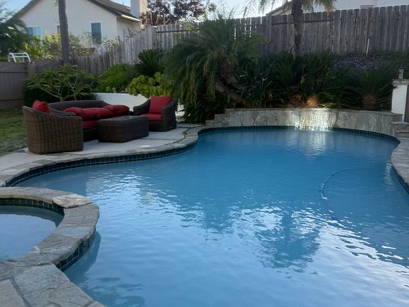 Pool with sunlit waterfall and pool sweep