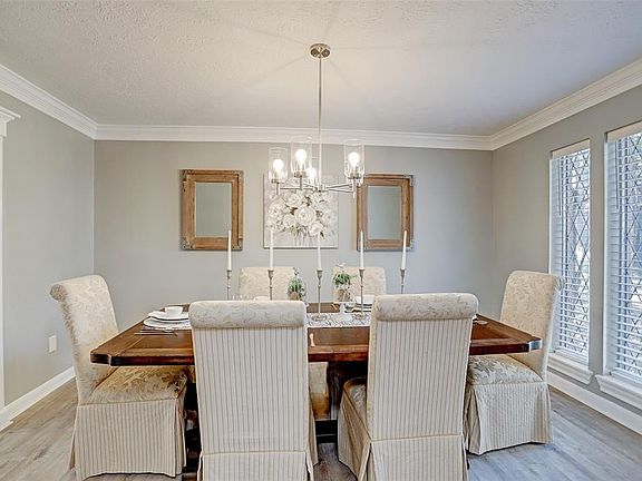 To the right of the entry is the Formal Dining Room with crown molding, vintage glass windows, new chandelier and wood laminate flooring