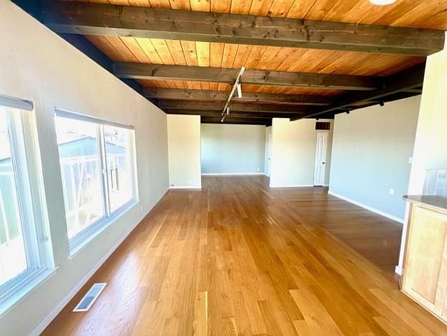 Living room/dining room has ample light, spectacular views, and attractive wood beam ceilings.