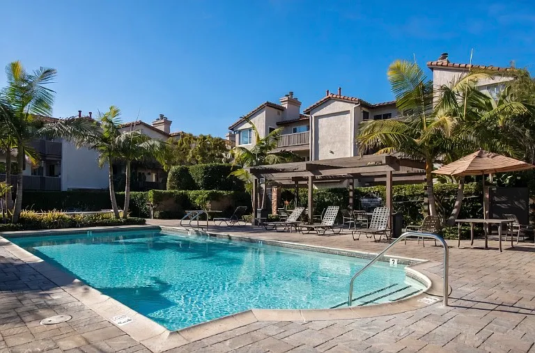 Relax by our sparkling community heated pool with palm trees and sunny skies.