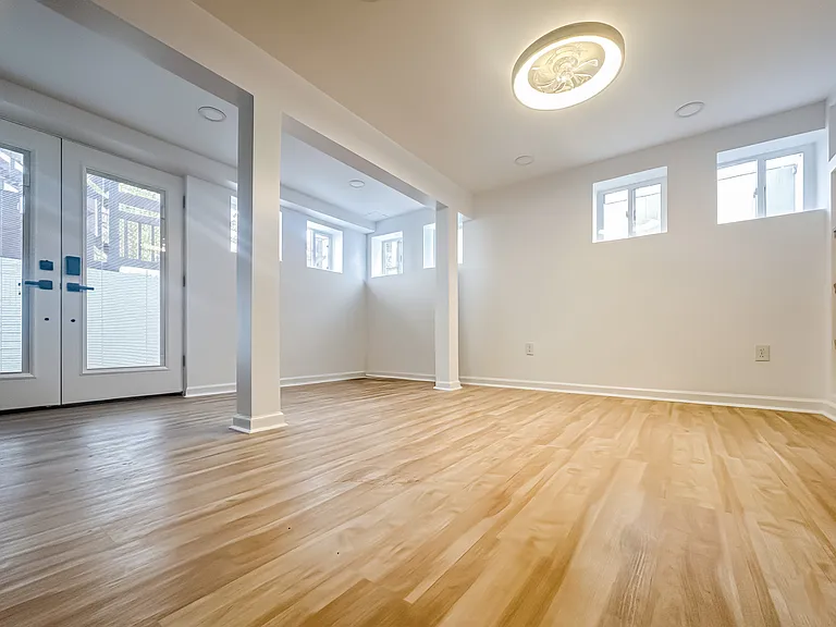Private enclosed three-season room with French doors, multiple windows, updated flooring, and bright natural light.