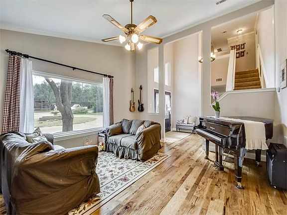 Front living area boasts soaring ceilings, picture window, and hardwood flooring.