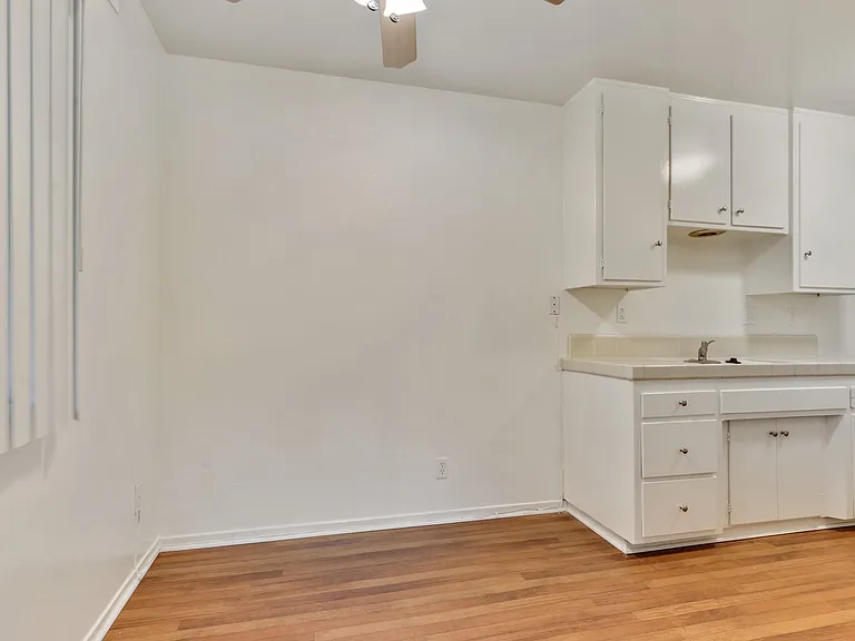 Dining area with Ceiling Fan, wood-inspired floors, kitchen on the right