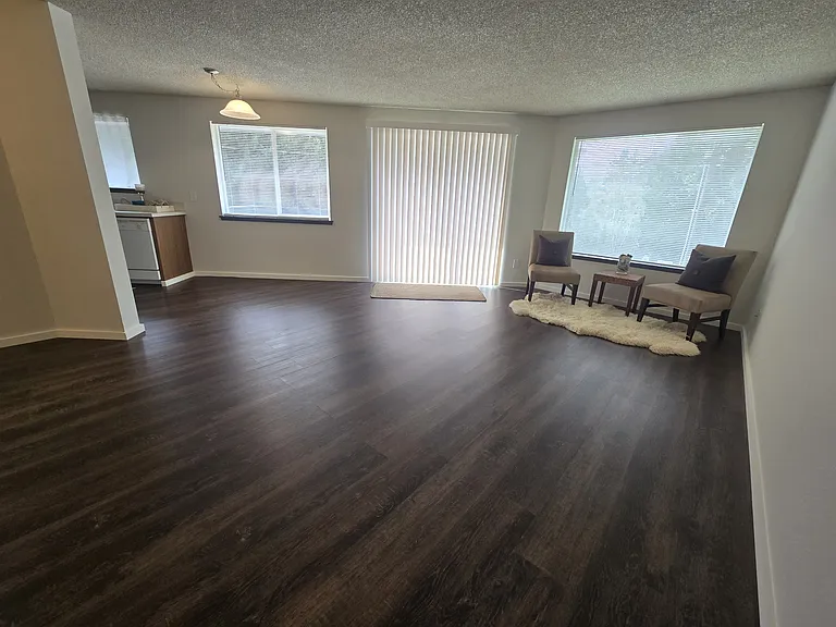 View of open plan layout of front room, slider to deck, dining area to kitchen. (rug, furniture not included).