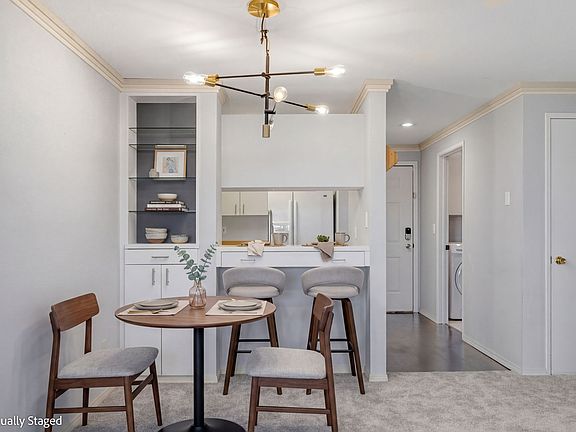 Dining area features a designer light fixture, pass through to the kitchen and built in cabinet.