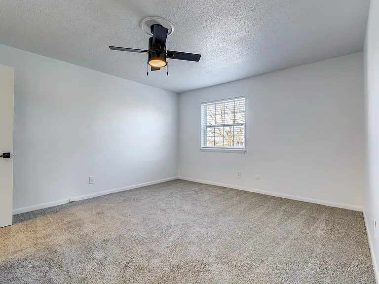 A carpeted bedroom with oversized closet and ceiling fan is shown at ReNew on Cantrell.