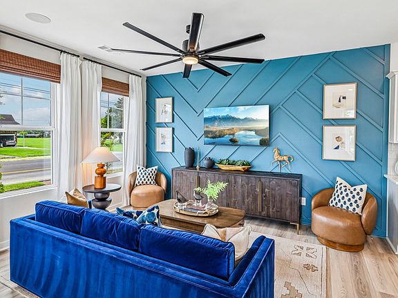Gathering room with ceiling fan, hard surface flooring, and accent wall
