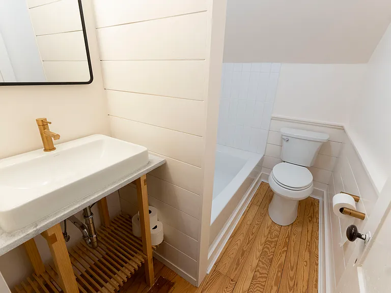 Brand new bathroom with brass fixtures, clean white tiles, beautiful hand crafted cedar vanity and ample tub