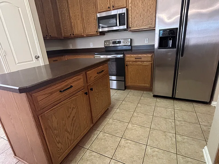 Standing at sink. More Cabinets, Large Island with storage underneath.