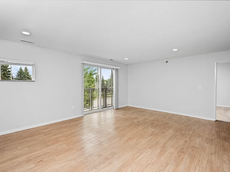 Bright living room with elegant hardwood floors, large sliding glass doors leading to a balcony, and a neutral color palette for a spacious feel. Bright living room with elegant hardwood floors, large sliding glass doors leading to a balcony, and a neutra