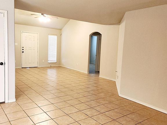 Looking from kitchen bar to front door. Bedrooms to right and interior garage door on left. Living area features vaulted ceiling.
