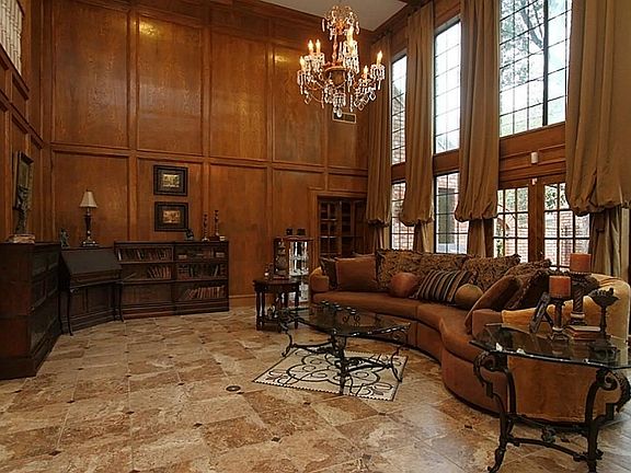 The grand den is an amazing place to entertain! The walls are adorned with custom oak wood panels & 18 ft custom silk drapes. Highlighting the room is a graceful antique chandelier above a custom tile mosaic. The floor is adorned with copper insert.