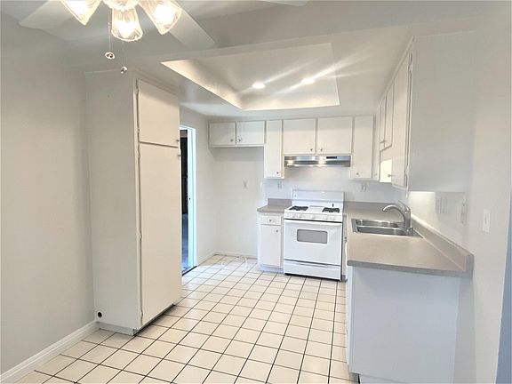 Kitchen viewed from dining area. Open door to the left is access to the garage. Dishwasher is to the right of sink.