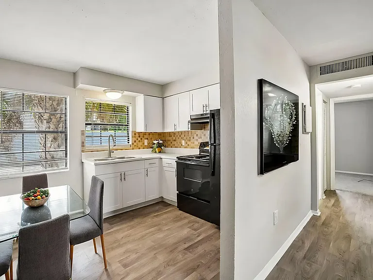 Charming apartment kitchen with white cabinets, modern appliances, and a cozy dining area bathed in natural light.