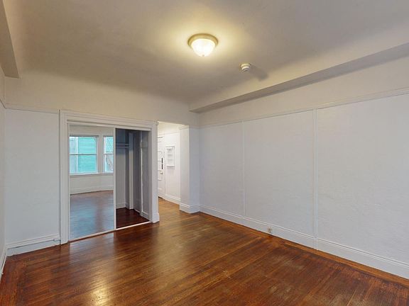 Bedroom with wood-like floor and a closet with mirror