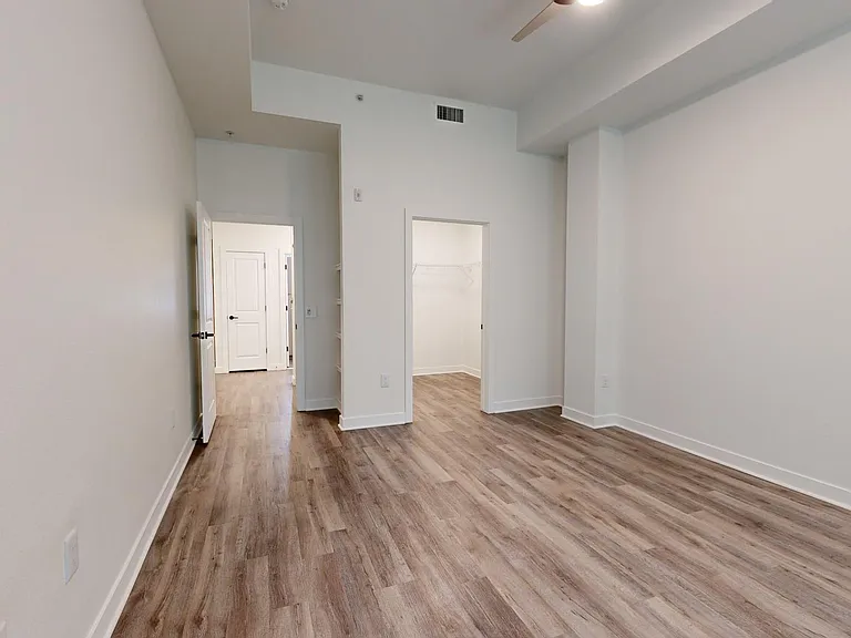 Spacious apartment bedroom with large closet and wood-style flooring.