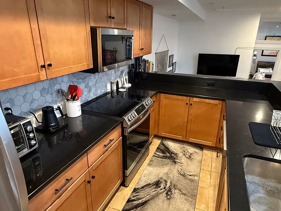 A tough-to-capture but open and wonderfully functional galley-style kitchen boasts brand new appliances and a raised breakfast bar with room for 4 stools