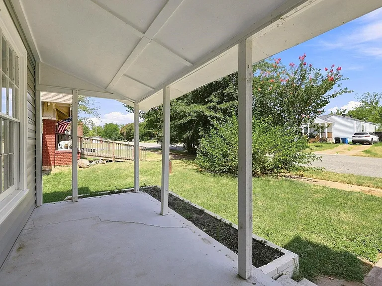 Covered concrete porch with white support posts