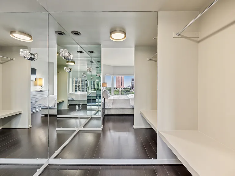 Mirrored walk-in closet with built-in shelving and generous hanging space.