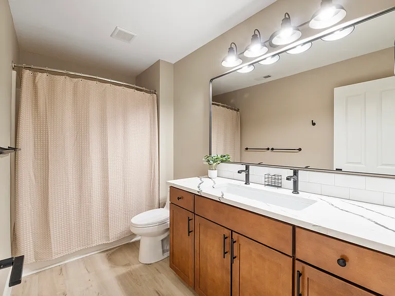 Guest bathroom with quartz countertops and trough sink with dual faucets