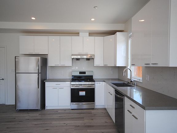 New kitchen with stainless steel appliances (5 burner stove), quartz countertop, modern backsplash, recessed LED lighting, and LTV flooring.