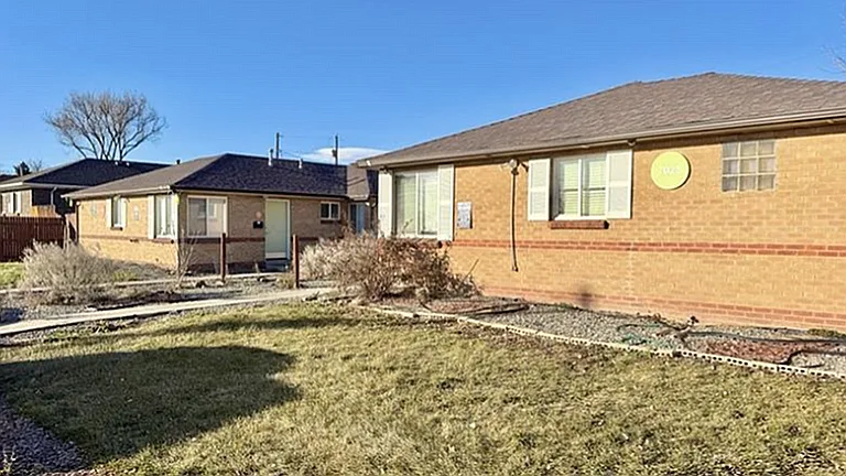 Charming brick duplex with large windows, nestled in a sunny, landscaped yard offering a welcoming suburban vibe.