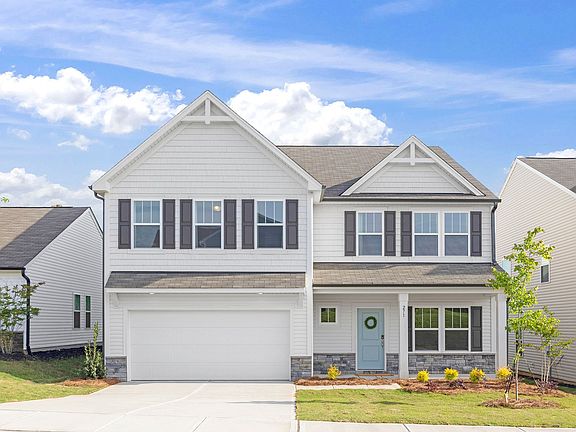 A white house with black shutters and a blue door is for sale.