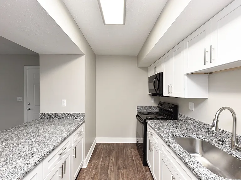 Kitchen with granite counters, black appliances, and modern cabinetry