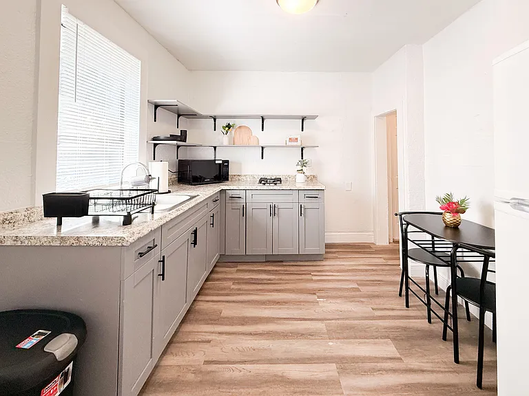 U-shaped kitchen with ample counter space, open shelving, a gas cooktop, and a breakfast nook for two.
