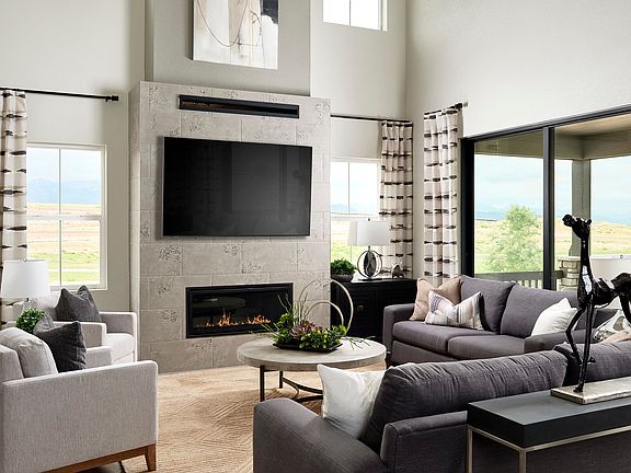 A spacious and modern living room with large windows, a fireplace, and a comfortable seating arrange