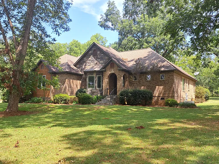 Exterior view of Arts and Crafts style home with primary construction materials of brick and stone