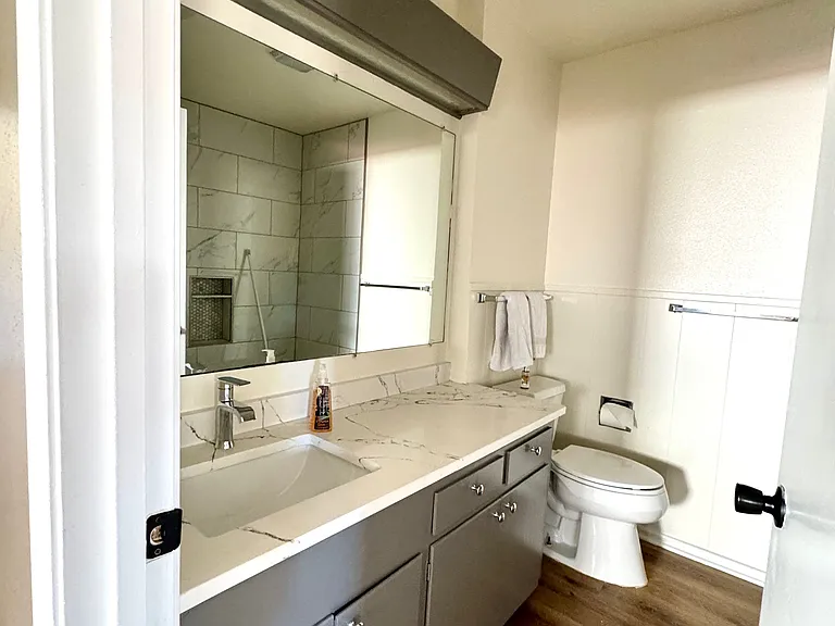 Hallway bathroom with quartz counters and a just remodeled bathtub with tile all the way up to the ceiling.