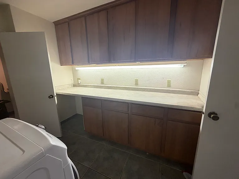 A spacious laundry and craft room with dual entrances offers exceptional functionality and organization, featuring additional built-in storage and plenty of workspace. The washer and dryer are included for added convenience.