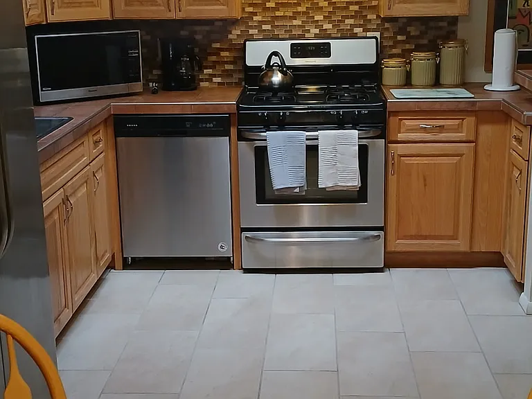 The spacious fully-equipped kitchen features tons of cabinet and prep space, tile cabinet tops, all stainless appiances: a gas range, a French door refrigerator, and a dish washer.