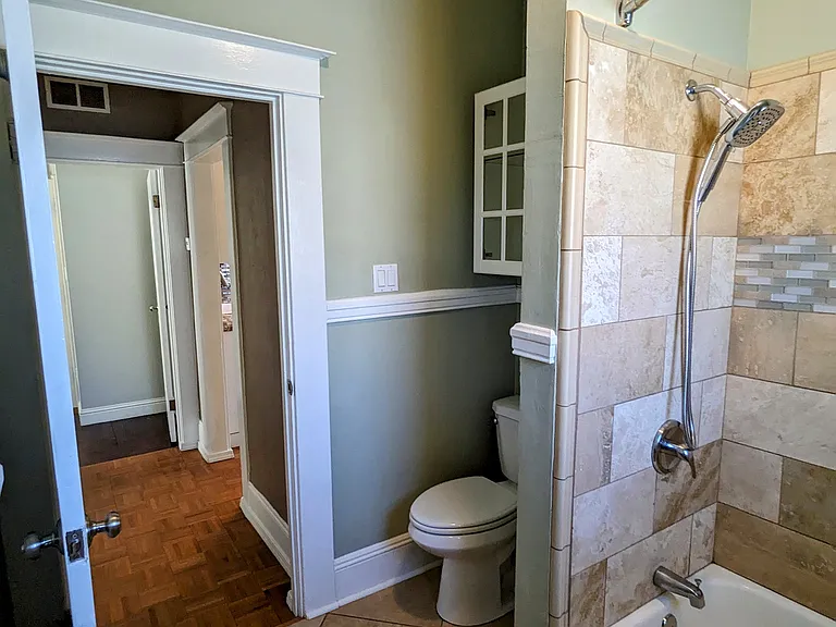 Elegant travertine floor and shower surround with mosaic tile accents.