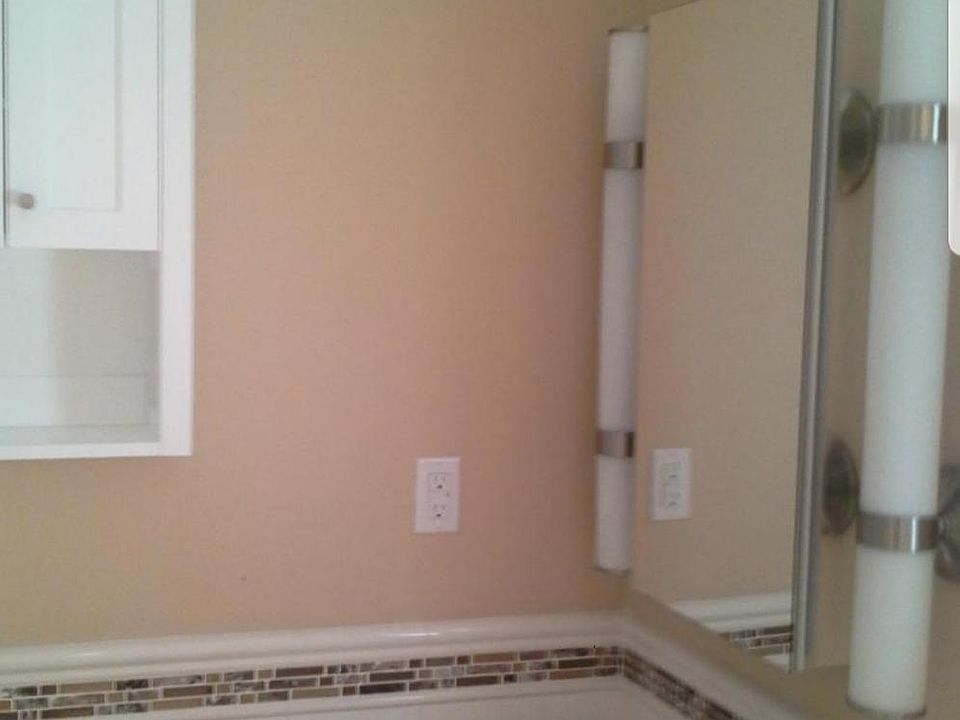 Bathroom has 2 cabinets and subway tile.